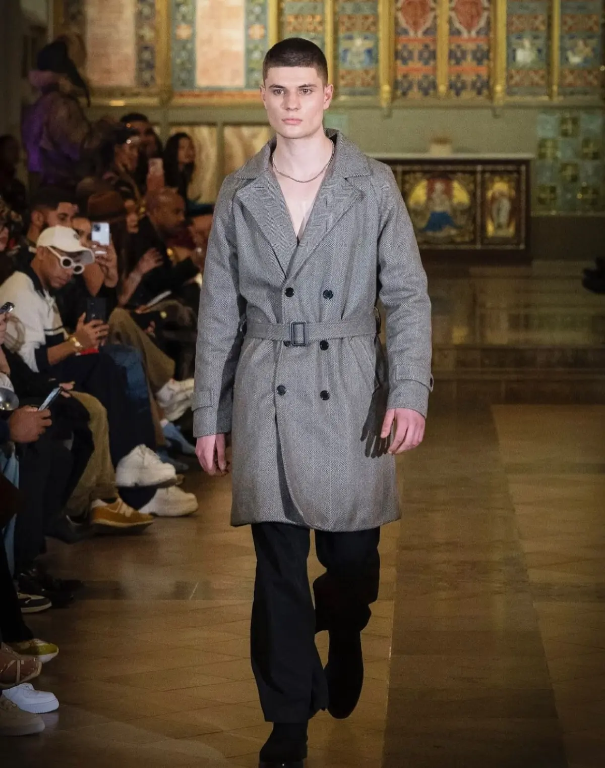 Lutfi Al Fathi walking a runway in a grey herringbone trench coat