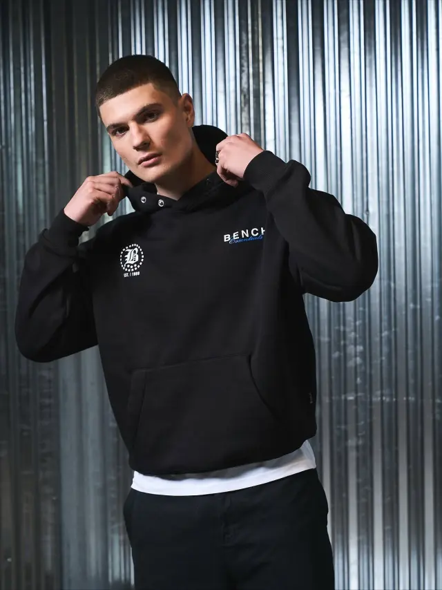 Lutfi Al Fathi in a black Bench hoodie against corrugated metal