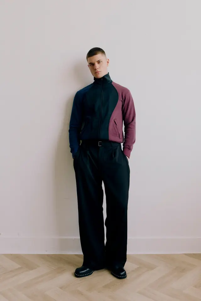 Lutfi Al Fathi full length in a navy and burgundy top and wide black trousers