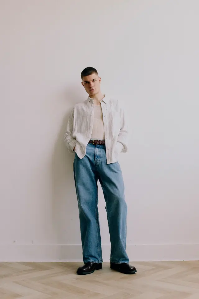 Lutfi Al Fathi full length in an open white shirt and blue jeans