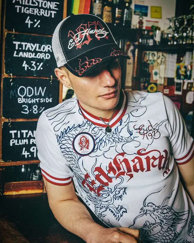 Lutfi Al Fathi in an Ed Hardy shirt and trucker cap inside a pub