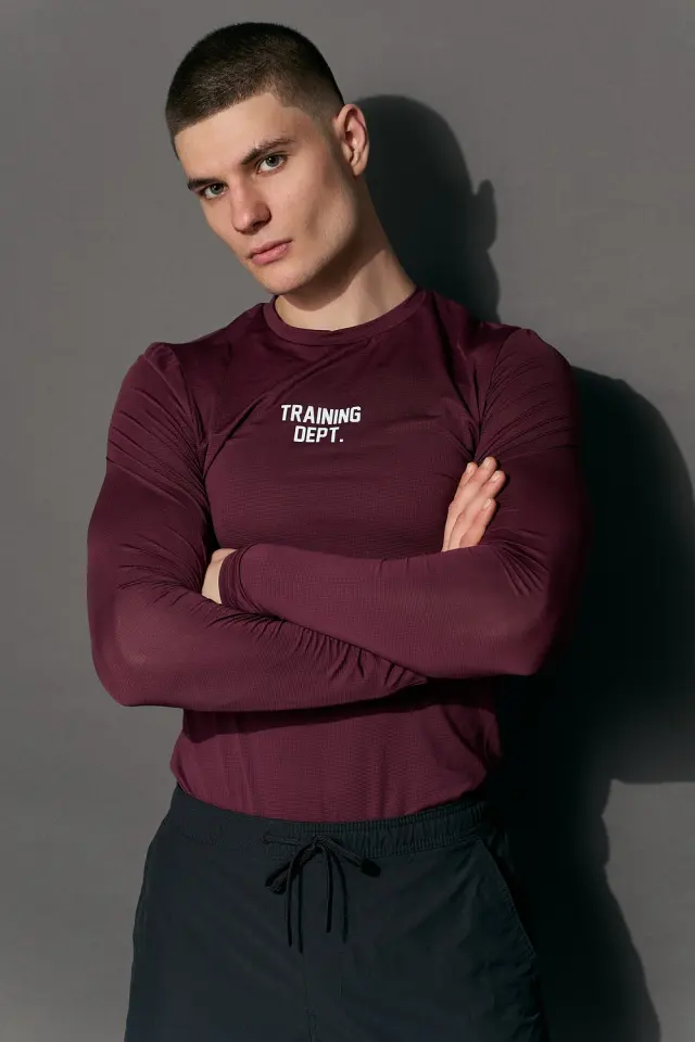 Lutfi Al Fathi with arms crossed in a burgundy long-sleeve training top